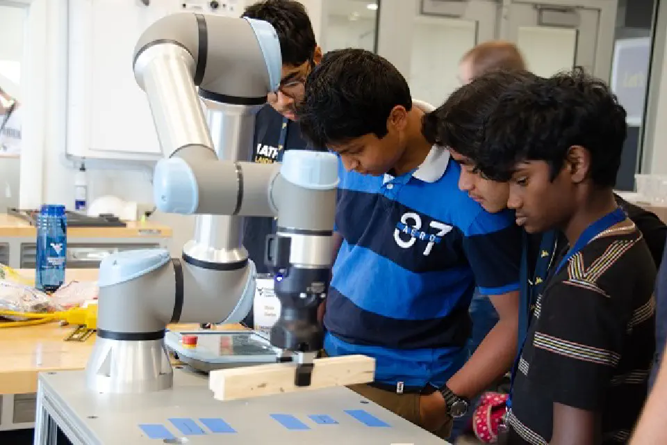 Youth participants working with a robotic arm on a table